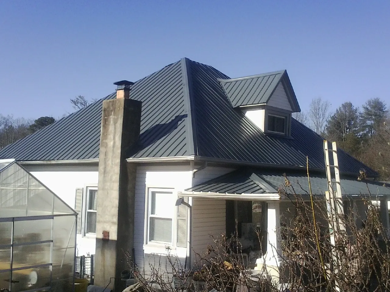 Dark blue standing seam metal roof on a white farmhouse with dormer — Slate & Tile Roof Repair by Roofing Brothers in Blue Ridge Summit