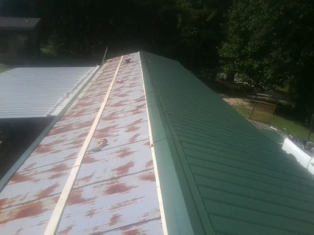 Old rusted panels beside newly installed green metal roofing — Wind Damage Roof Repair by Roofing Brothers in Blue Ridge Summit