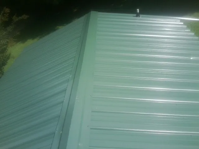 New green metal panels meeting at the ridge of a roof — Flat Roof Repair work by our crew in Blue Ridge Summit