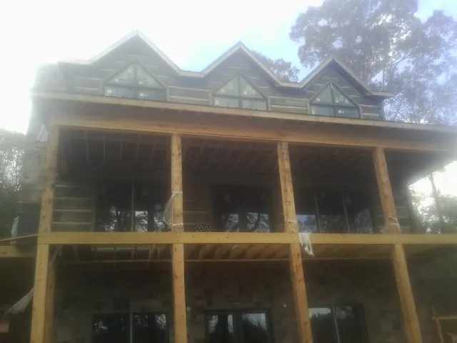 Dormers and porch framing on a large log home under construction — Roof Coating work by our crew in Blue Ridge Summit