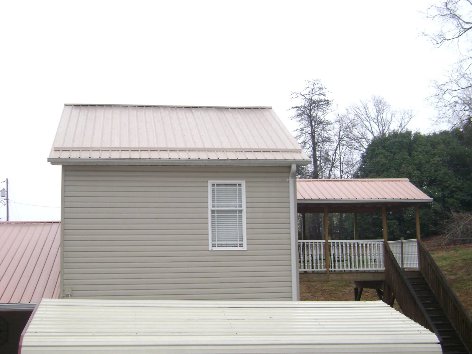 Tan metal roofs on a two story addition and attached porch, from a Roof Replacement job in Blue Ridge Summit