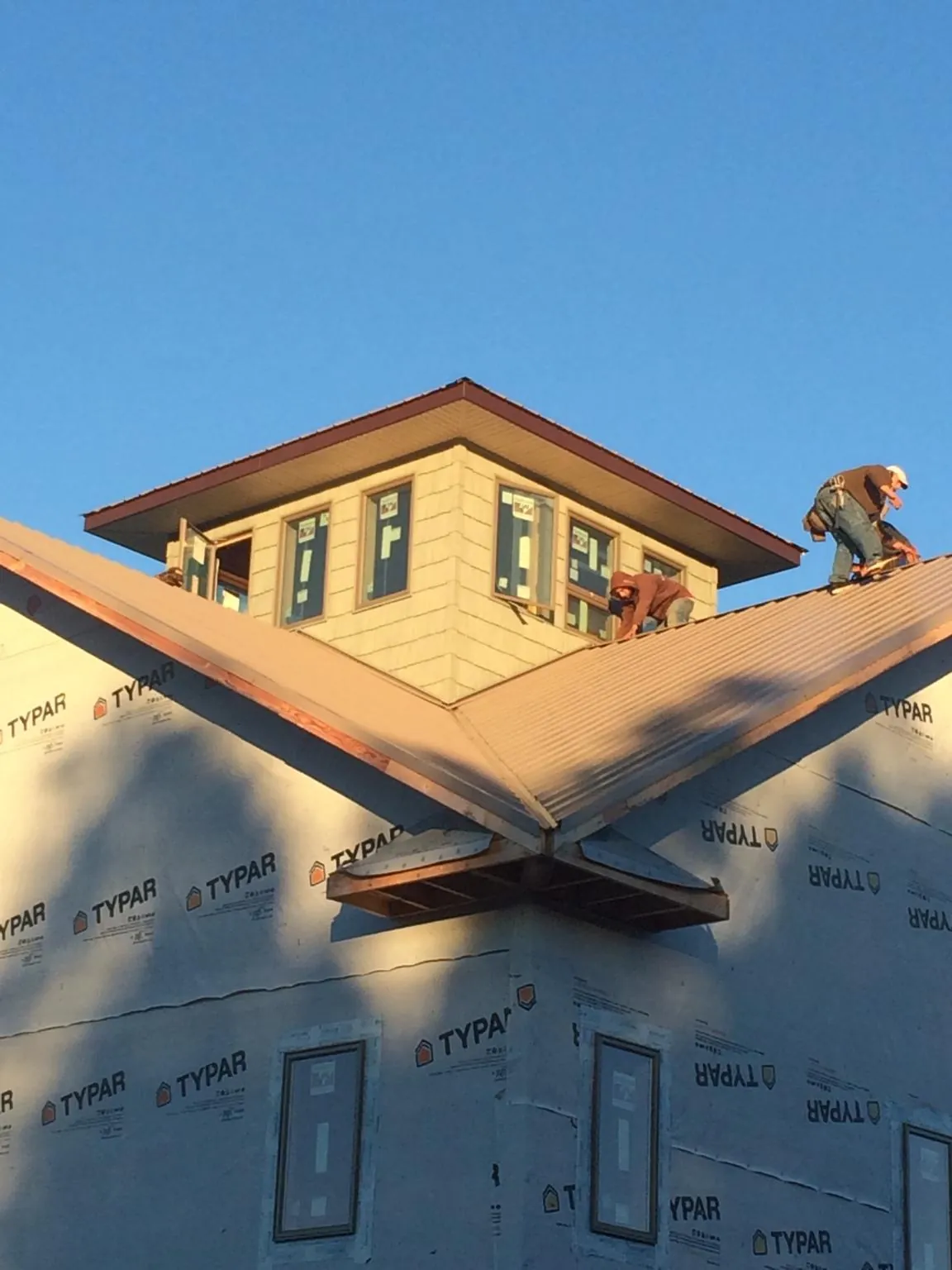 Roofers working around a rooftop cupola on a new metal roof at sunset — Roof Waterproofing in Blue Ridge Summit by Roofing Brothers